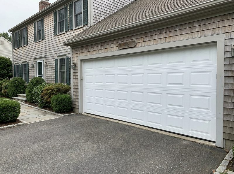 A new insulated steel raised-panel garage door on a New England colonial