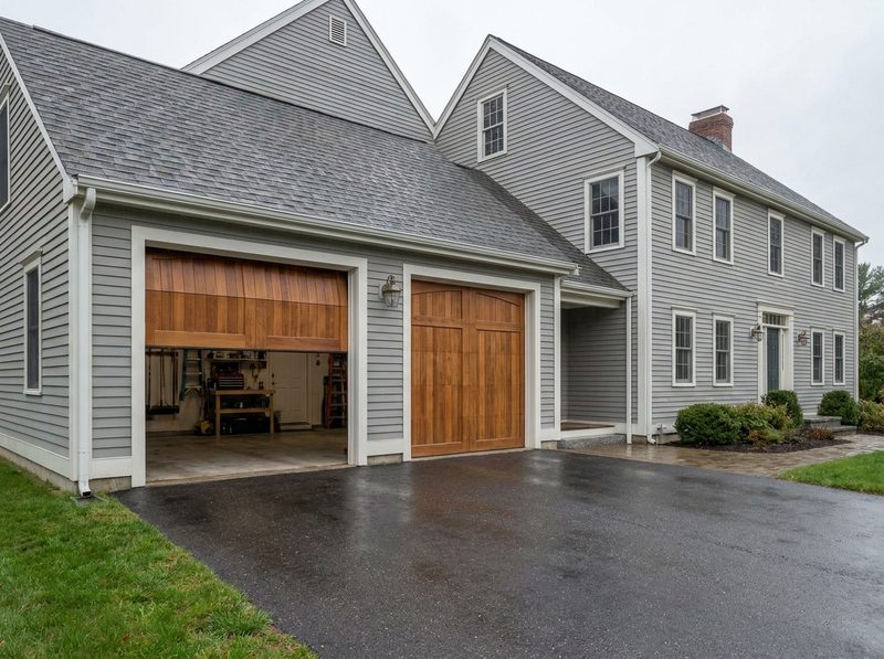 A two-car garage on a New England colonial with one door raised halfway